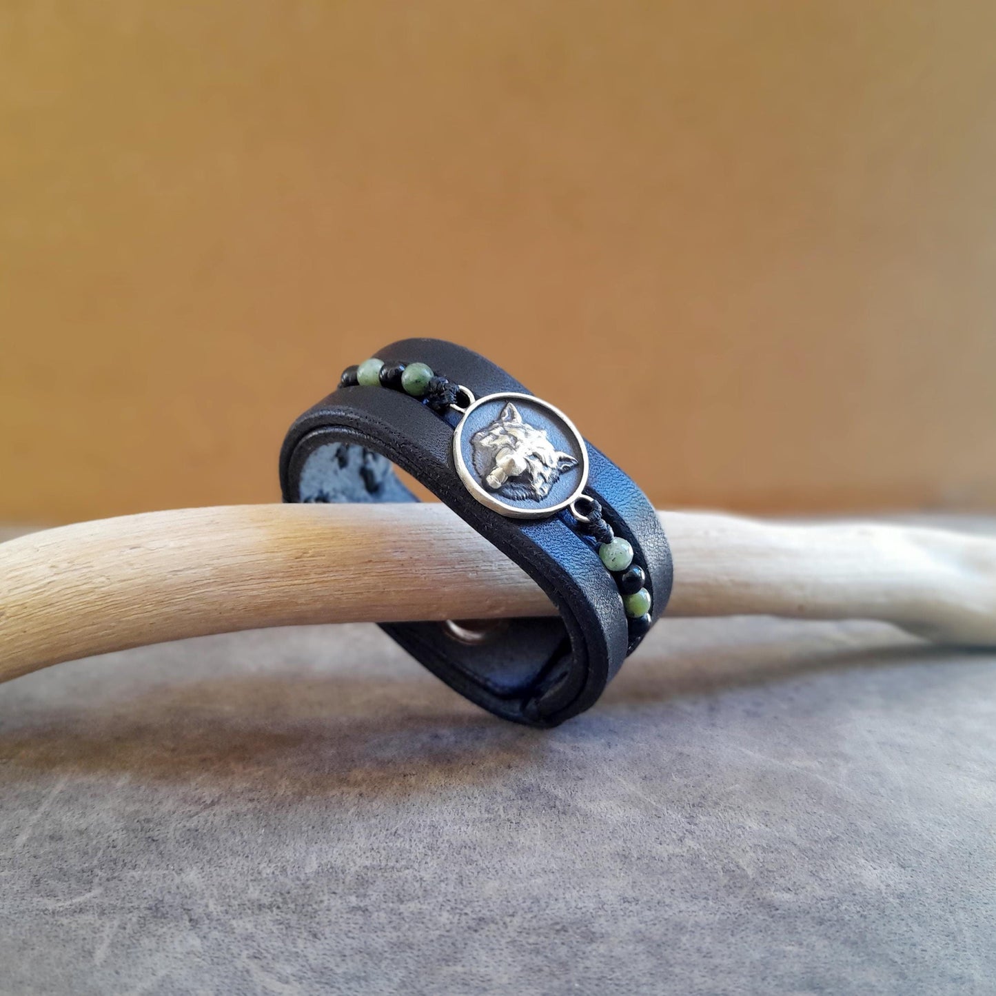 Triple-layer black leather lone wolf bracelet featuring brass pendant and onyx beads.