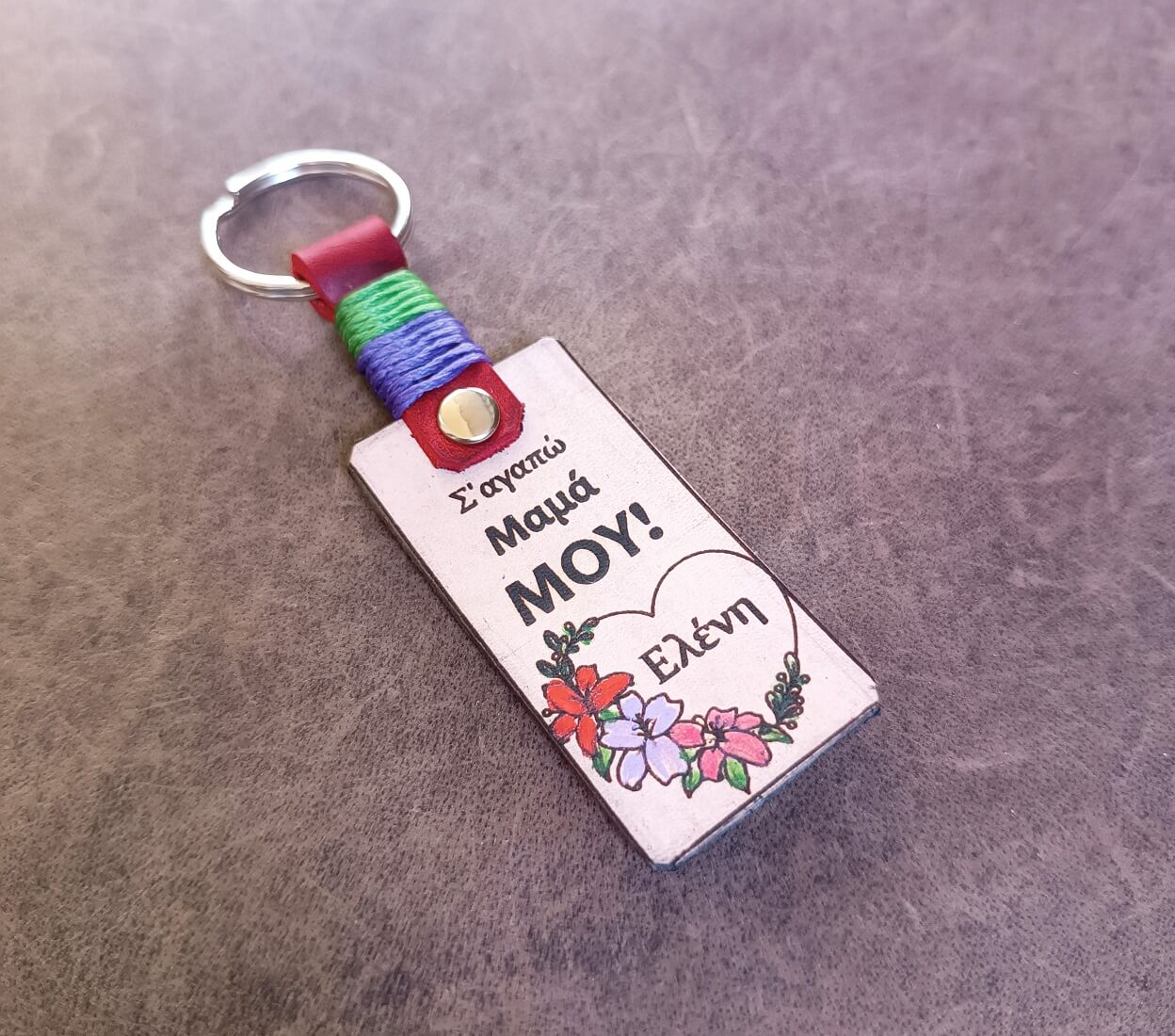 Keychain with colorful strap and engraved text on a gray background