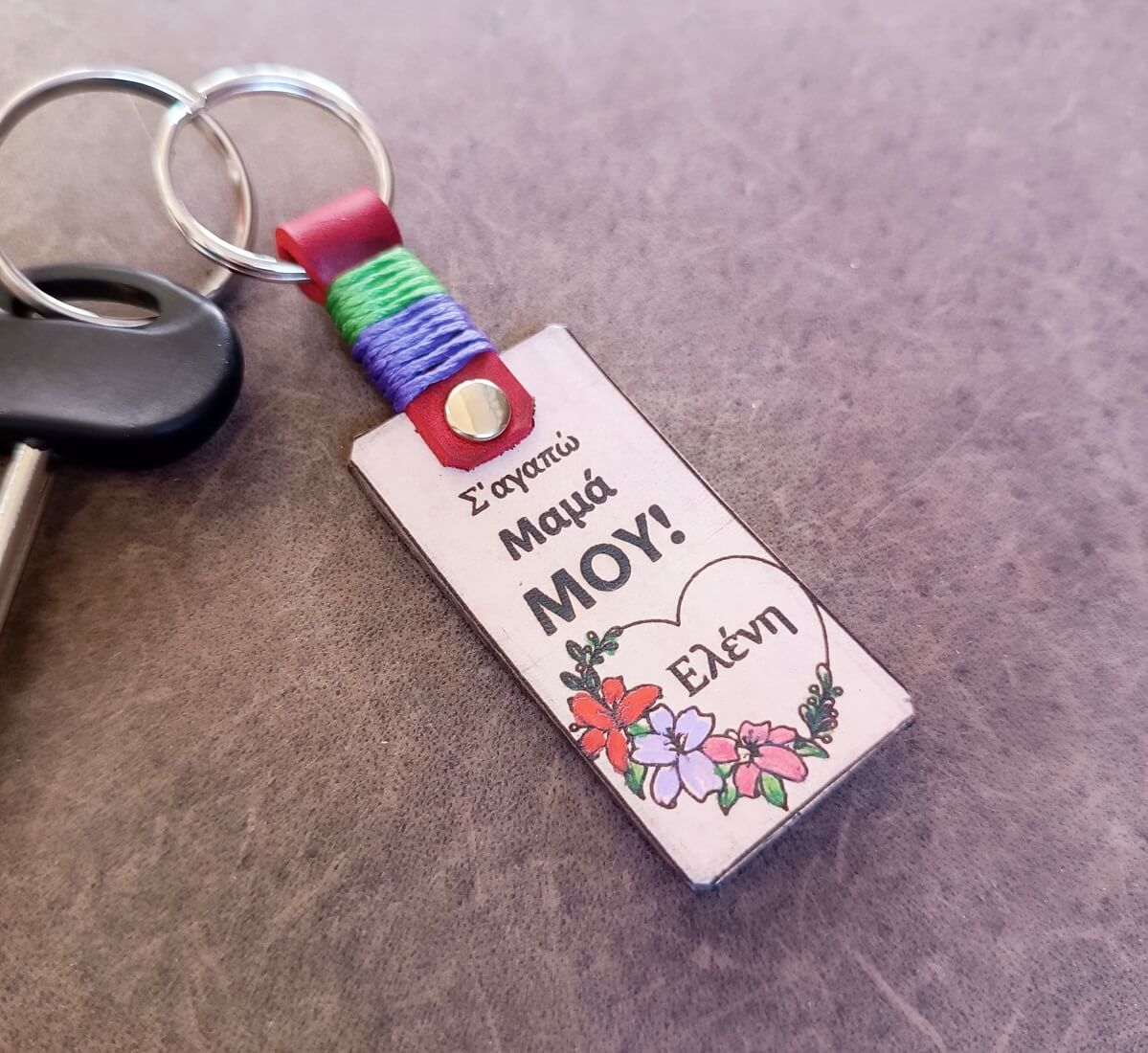 Keychain with colorful strap and floral design on a gray surface