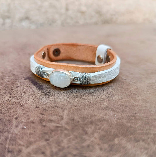 A handcrafted one-of-a-kind women's leather bracelet featuring a hand-cut natural moonstone set in sterling silver on raw untreated vachetta leather.