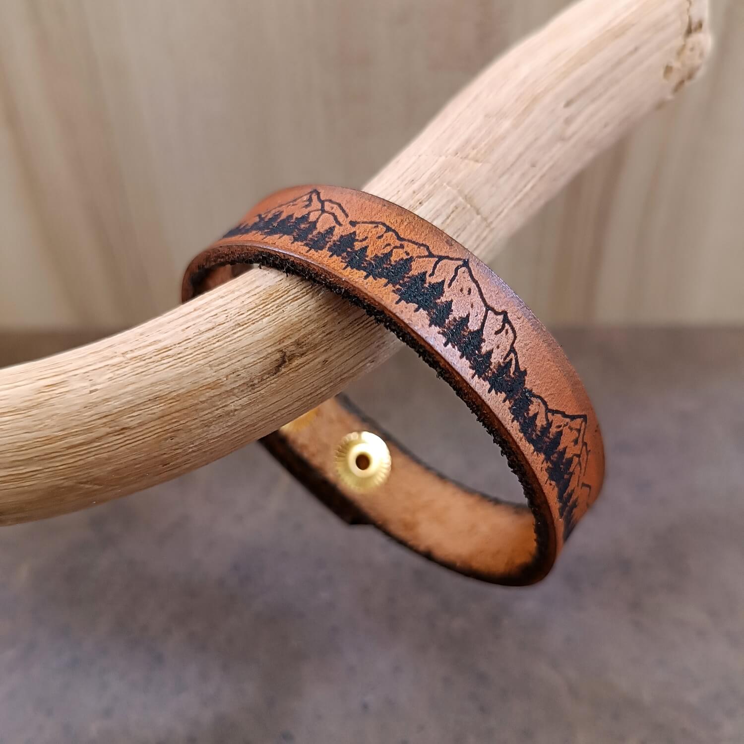 Brown leather bracelet with nature design on a wooden stick
