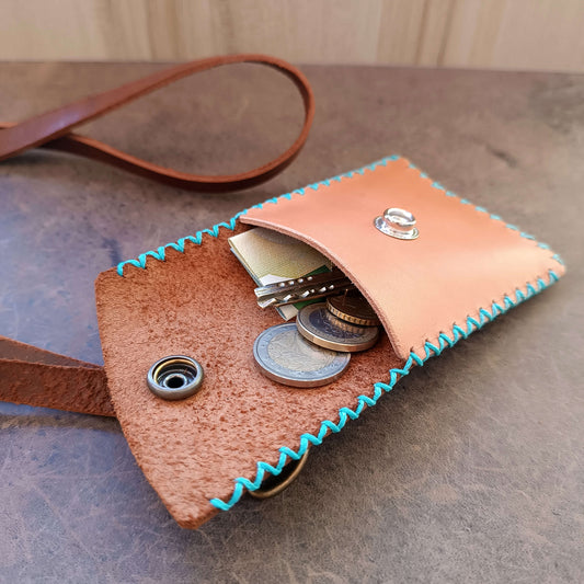 Leather coin purse open with coins , cash and keys on a textured surface