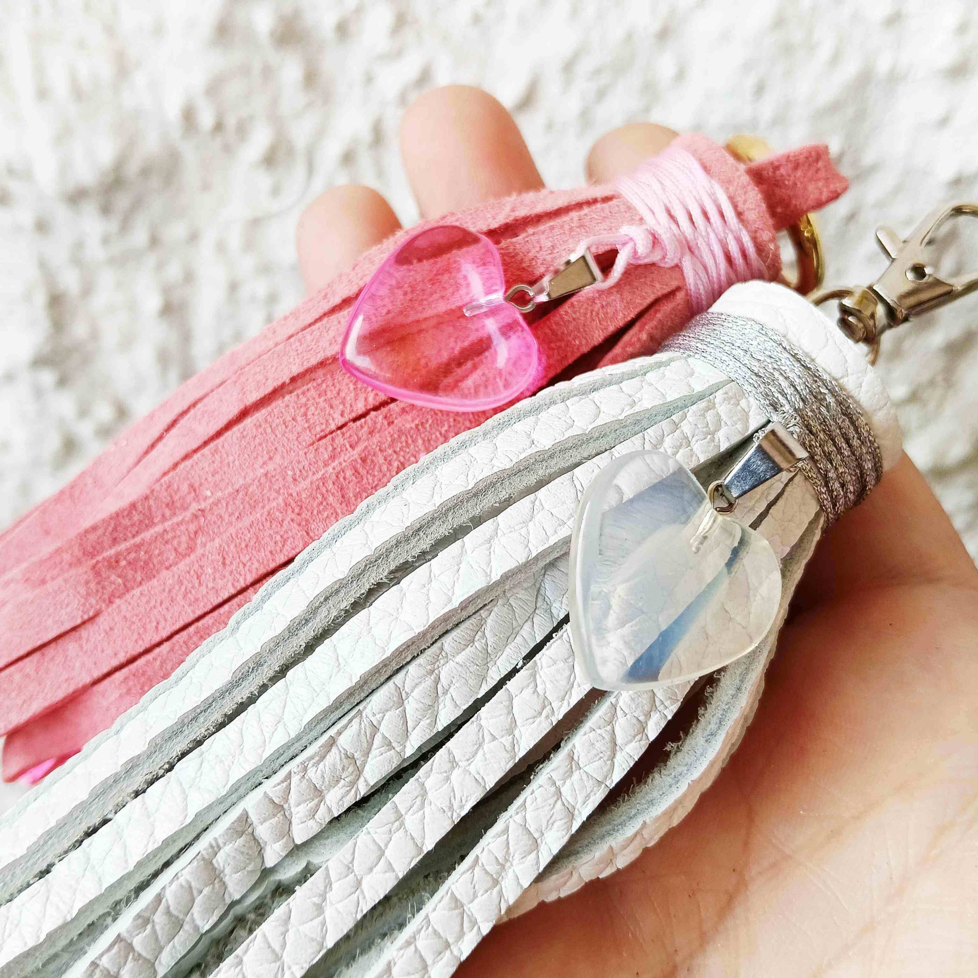 close up shot of the white and pink tassel bag charms held on hand