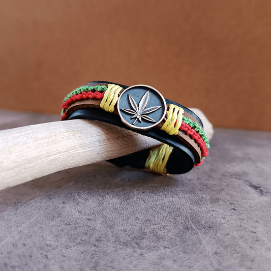 Bracelet with cannabis leaf charm on a wooden stick against a brown background