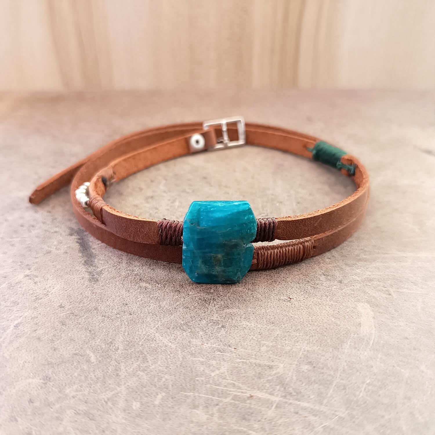 Brown leather choker with a blue stone on a textured surface