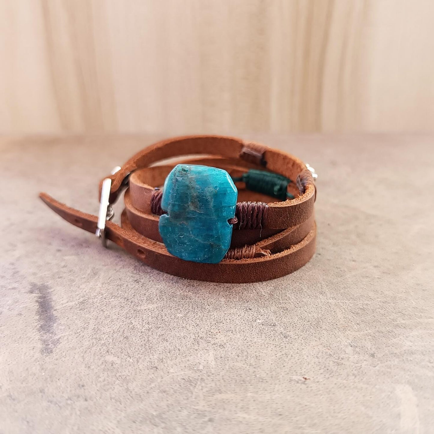 Brown leather bracelet with a blue stone on a light gray surface