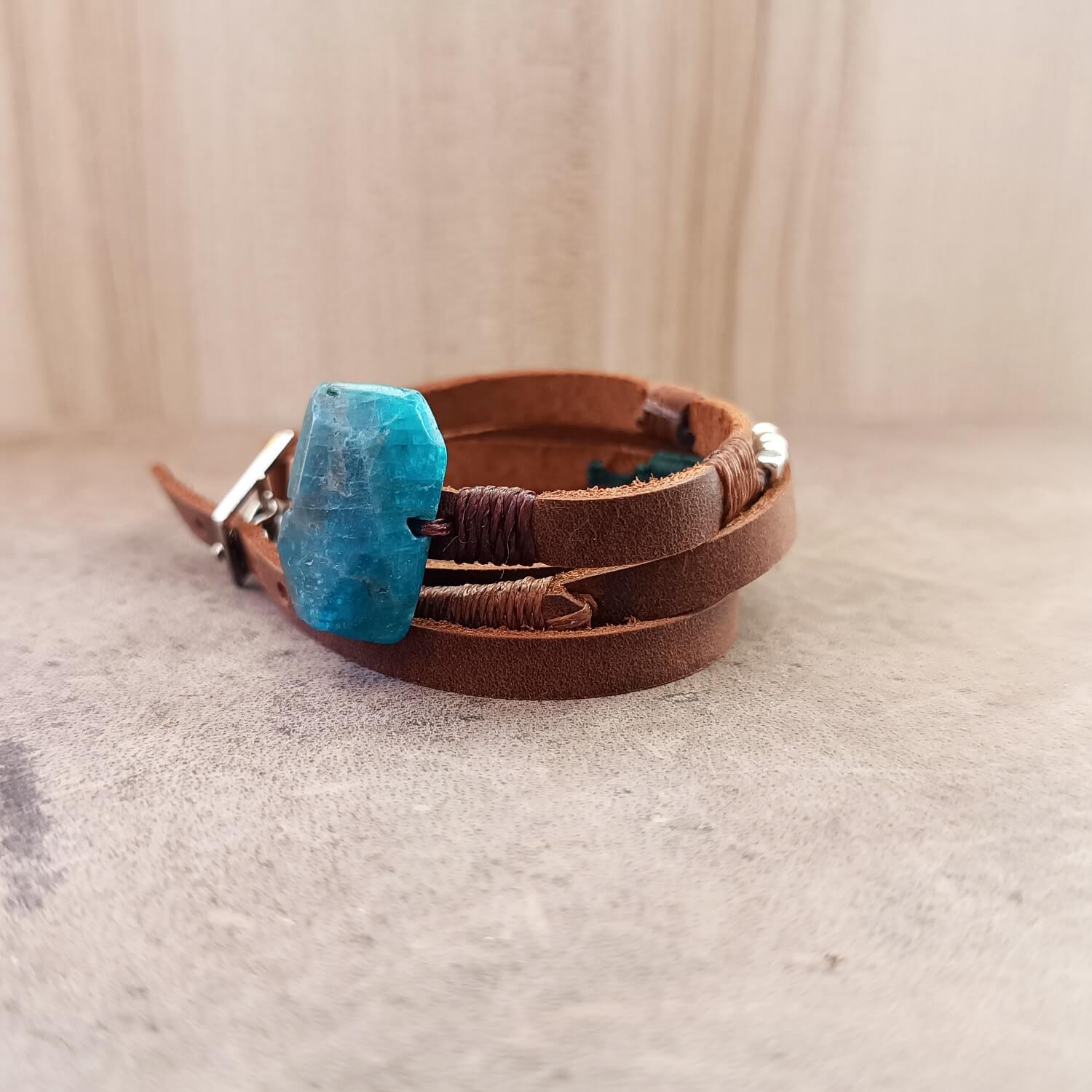 Brown leather bracelet with a blue stone on a beige background