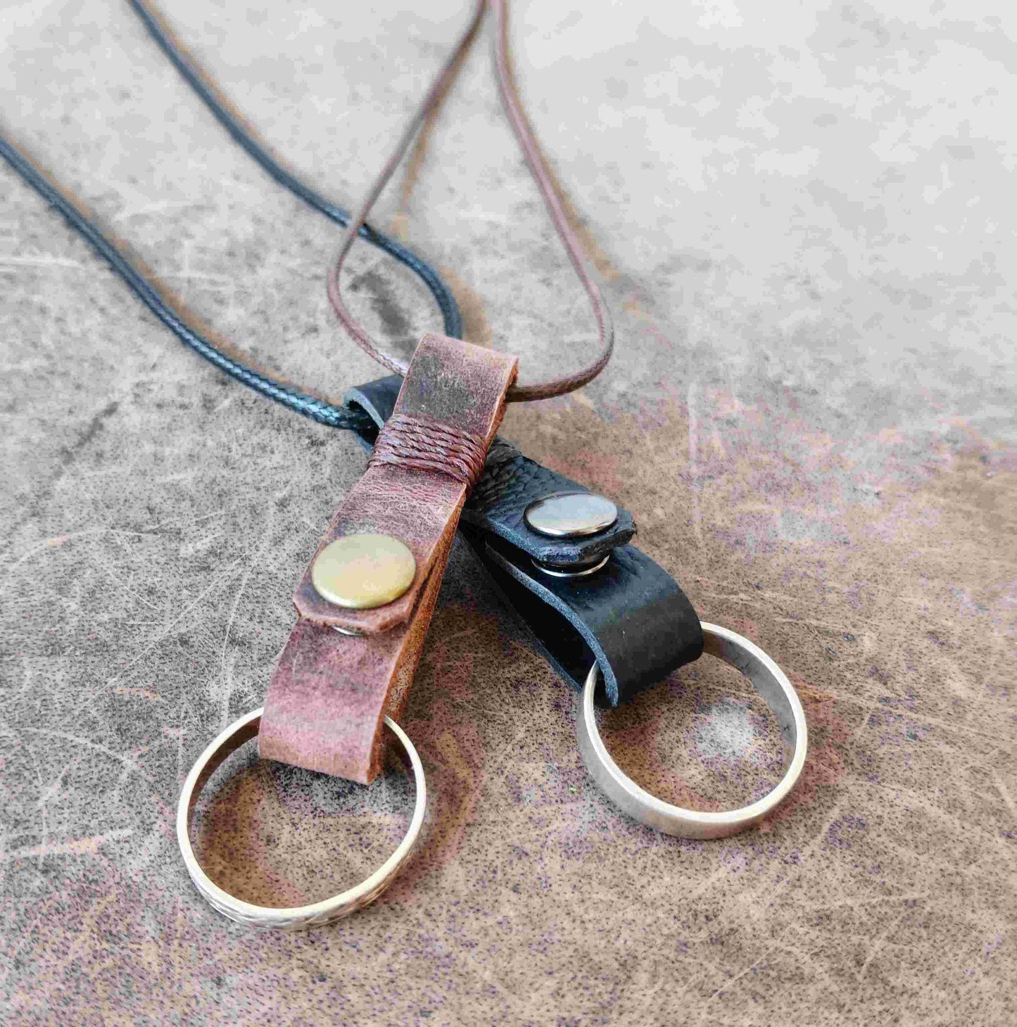 Two handmade leather ring holder pendants that carriy your ring close to your heart. Choose black or dark brown leather, with an optional matching adjustable cord.