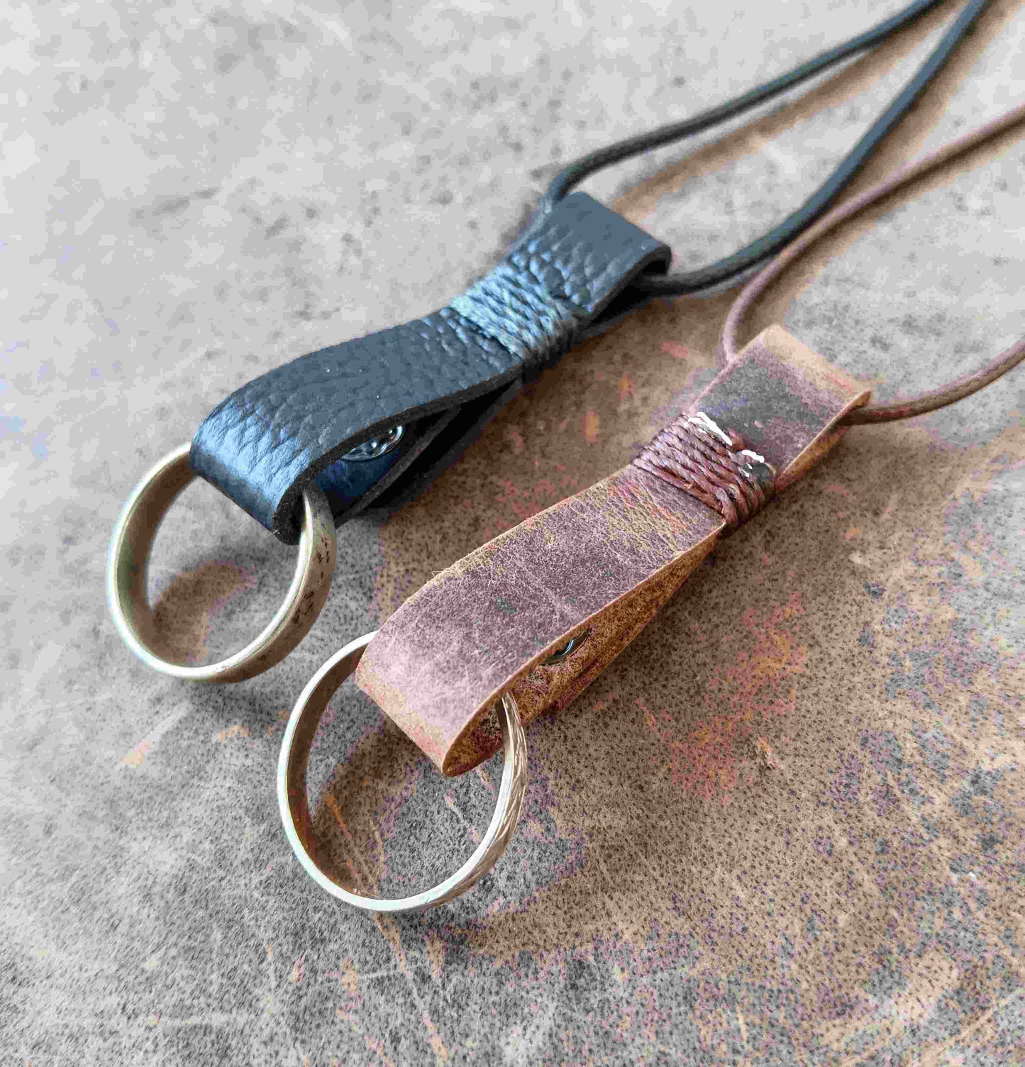Two handmade leather ring holder pendants that carriy your ring close to your heart. Choose black or dark brown leather, with an optional matching adjustable cord.