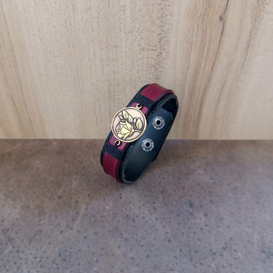 Bracelet with a gold brass rose pendant on a wooden surface