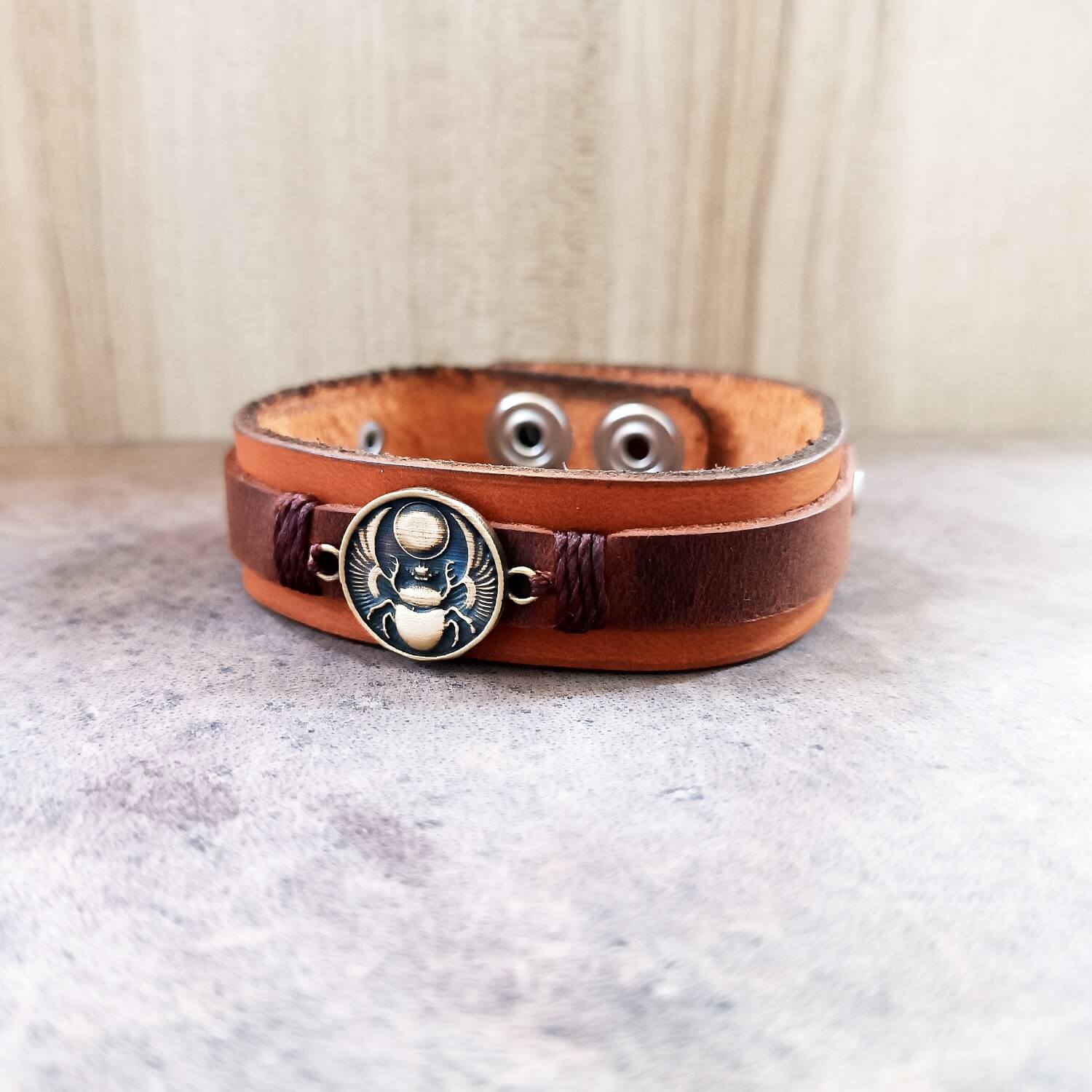 Brown leather bracelet featuring a winged scarab pendant