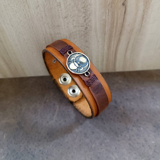 Brown leather bracelet with a scarab pendant on a wooden surface