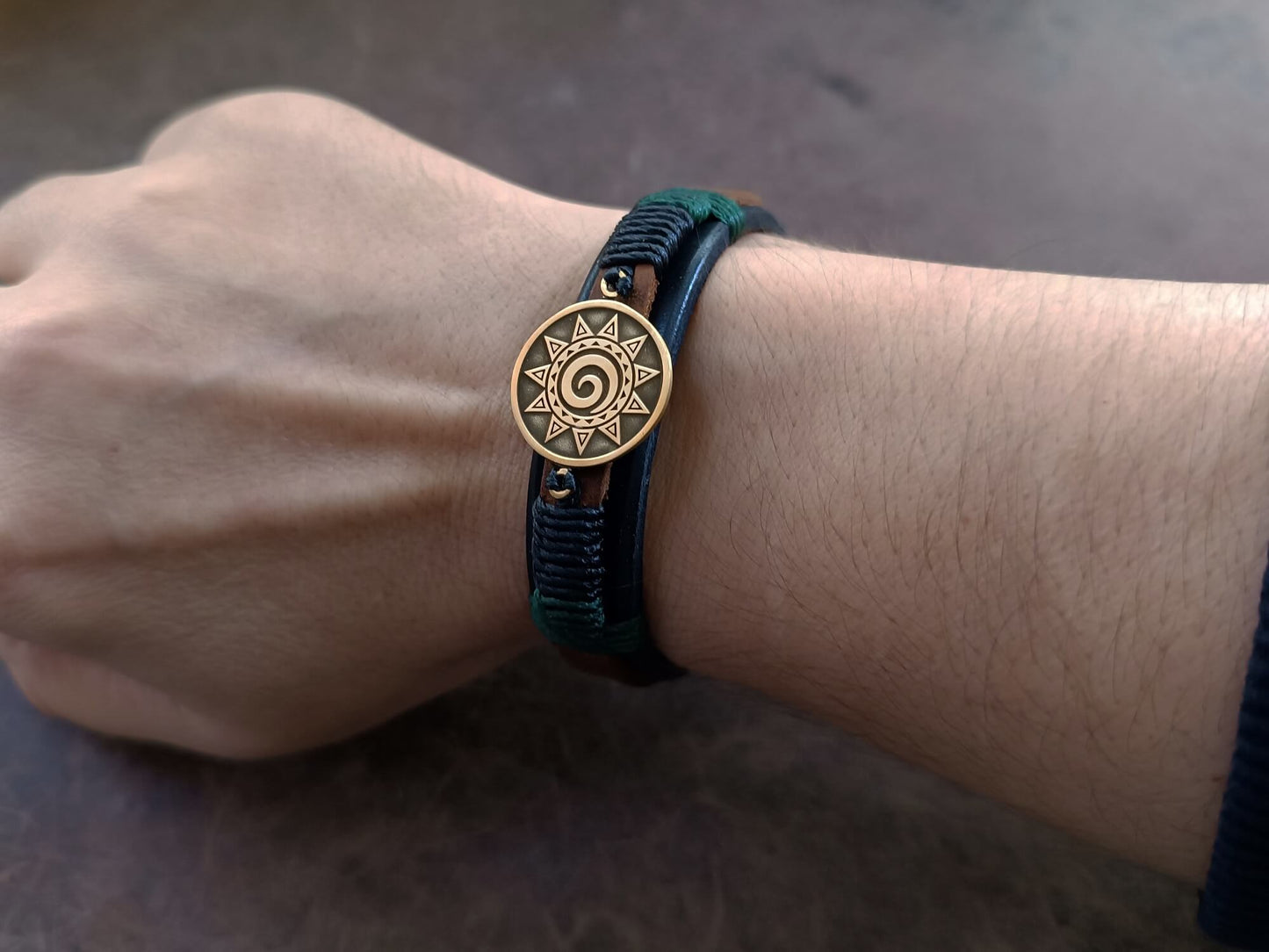 Unisex leather Koru bracelet worn on wrist, showing its slim 1.5 cm width and adjustable stud button closure.