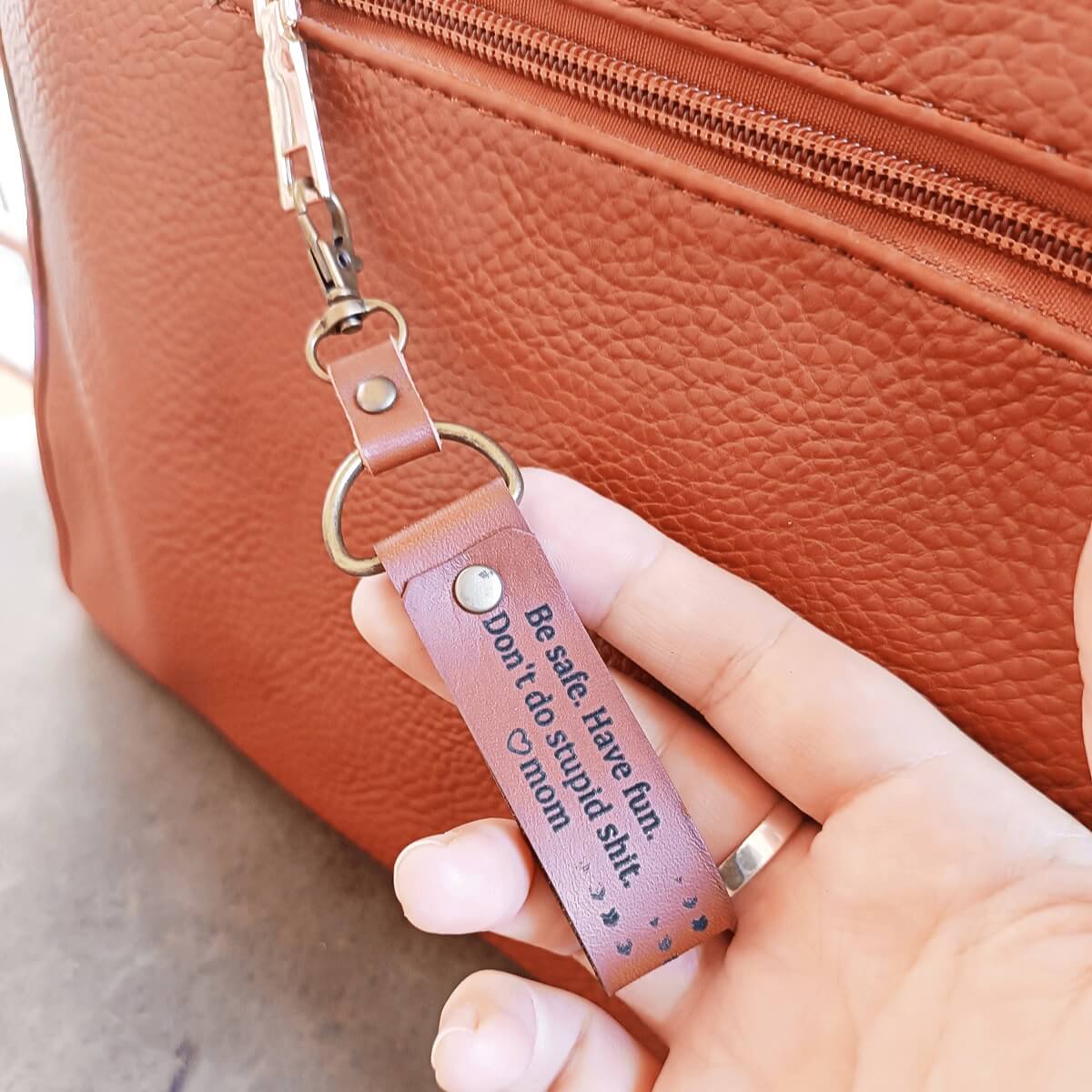 the brown leather keychain for long distance students and grown-up kids away from home, clipped on a bag.