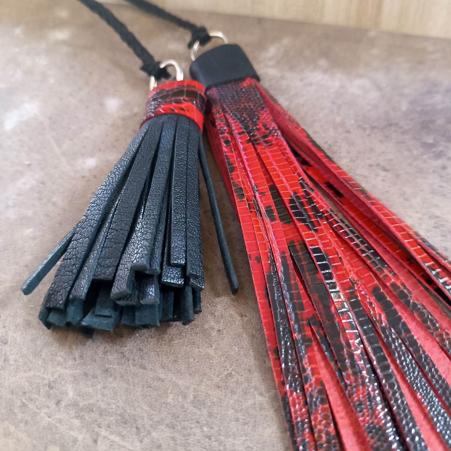 Black and red leather tassels on a textured surface