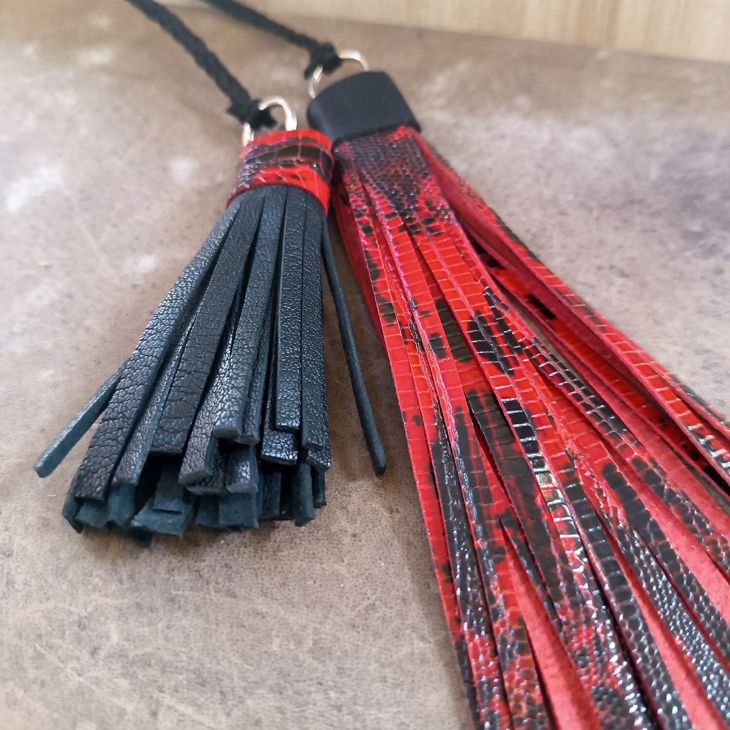 Black and red leather tassels on a textured surface
