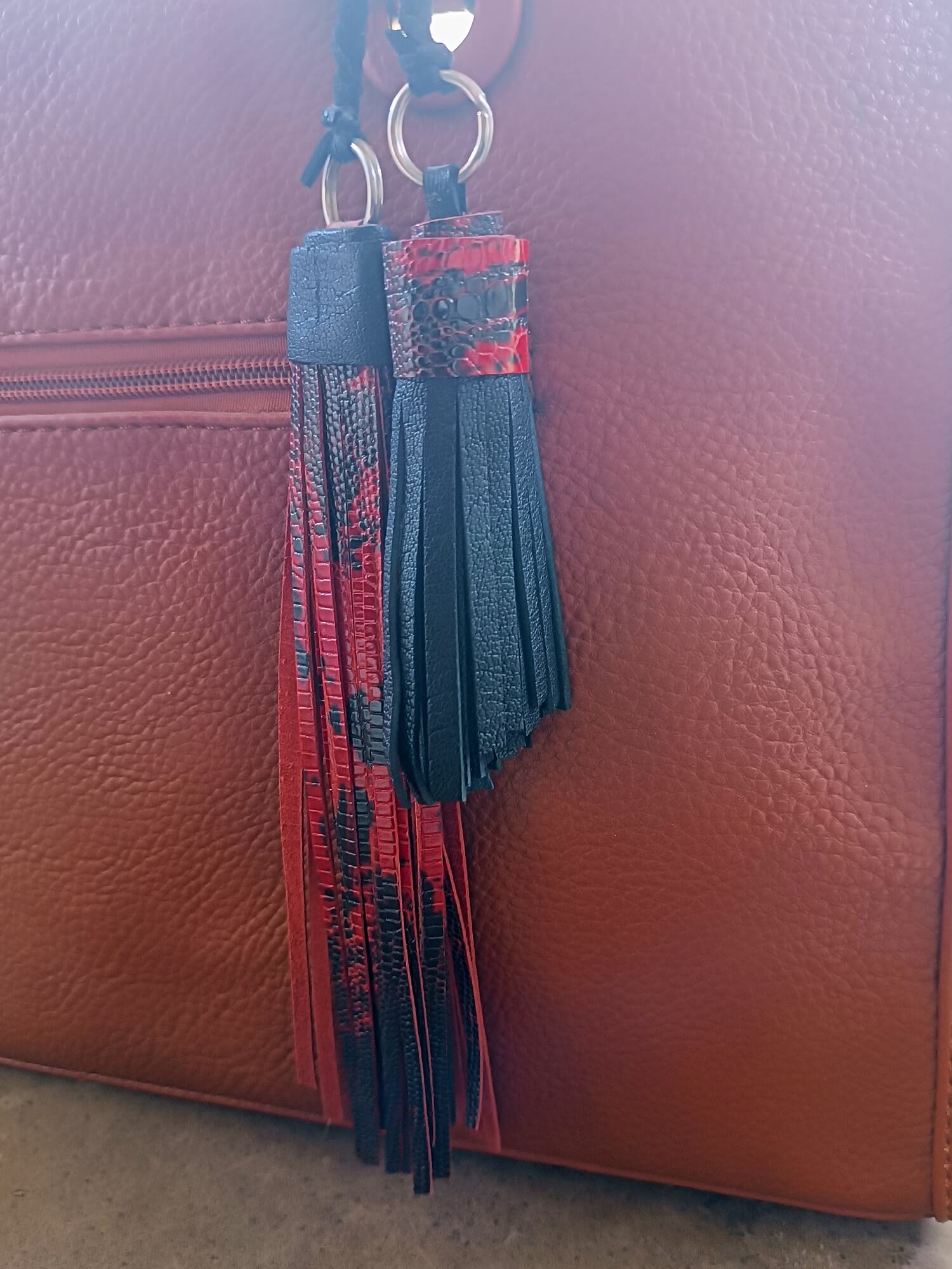 Black and red tassel keychain on a brown leather bag