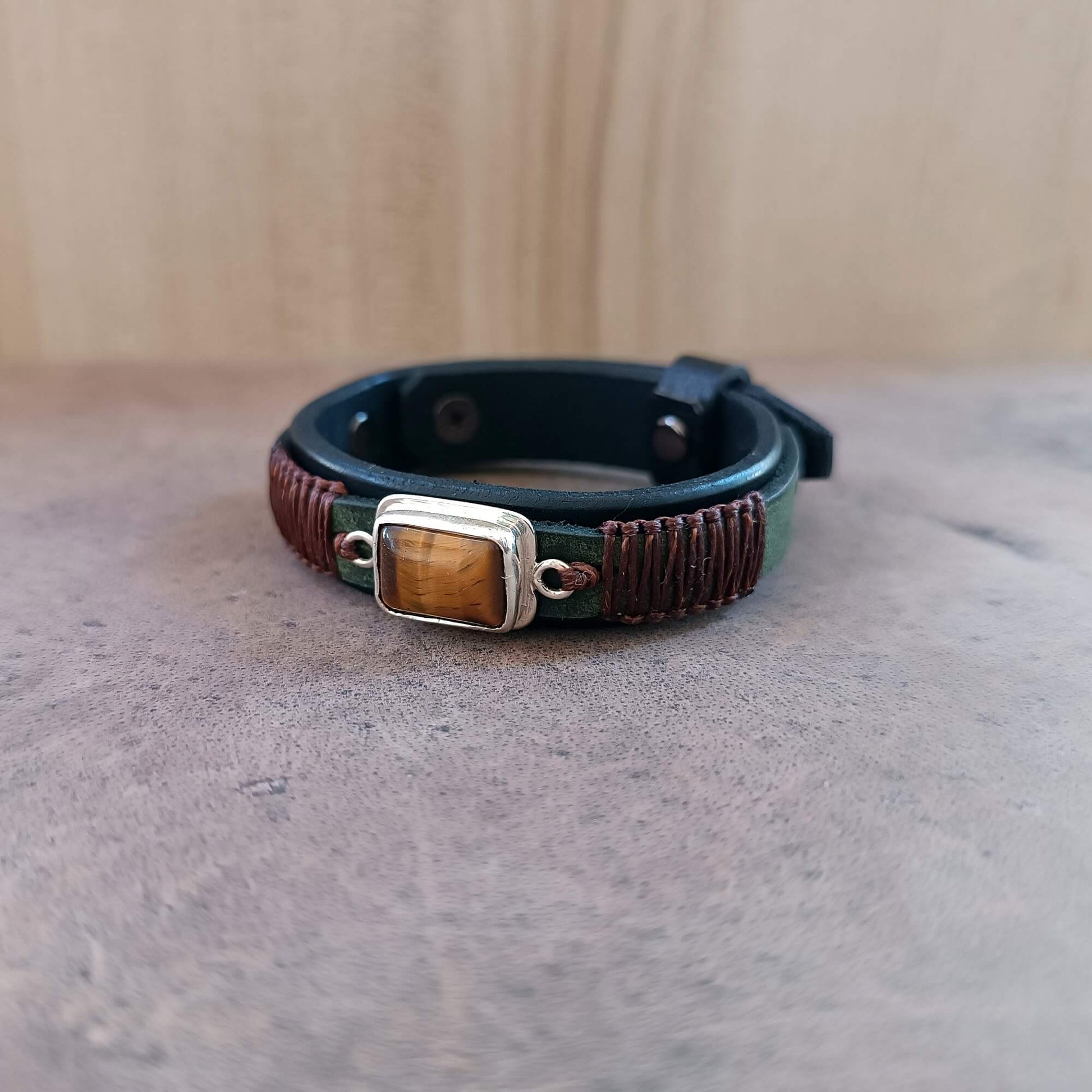 Premium Black Oiled Vachetta Leather Bracelet in watchband style, featuring a khaki green crazy horse top layer, dark brown macrame and a solid sterling silver pendant with a hand cut Tiger's Eye stone.