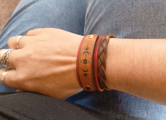 Close-up of a wrist wearing multiple leather bracelets with intricate designs.
