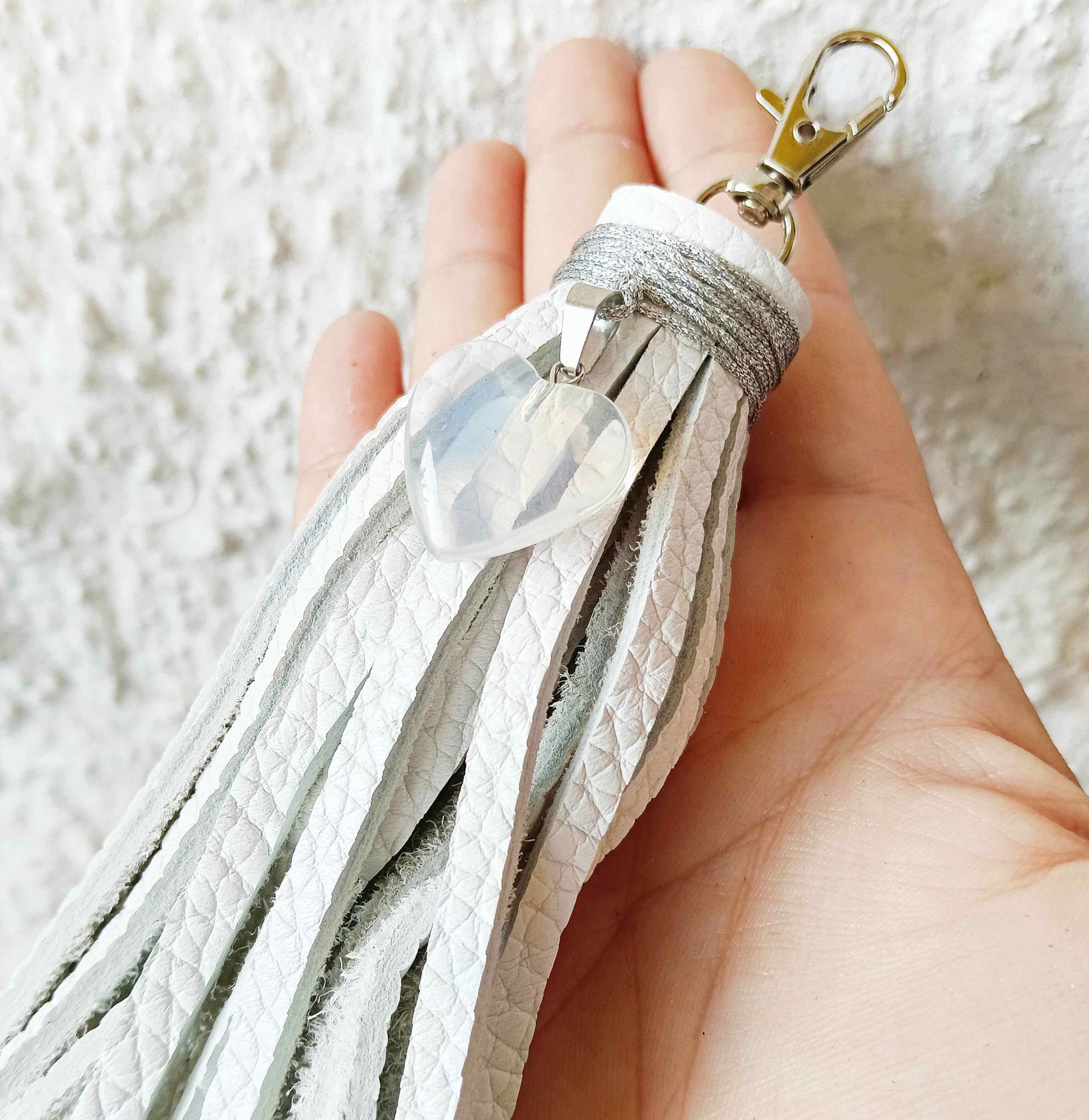 the white heart pendant tassel bag charm held in hand