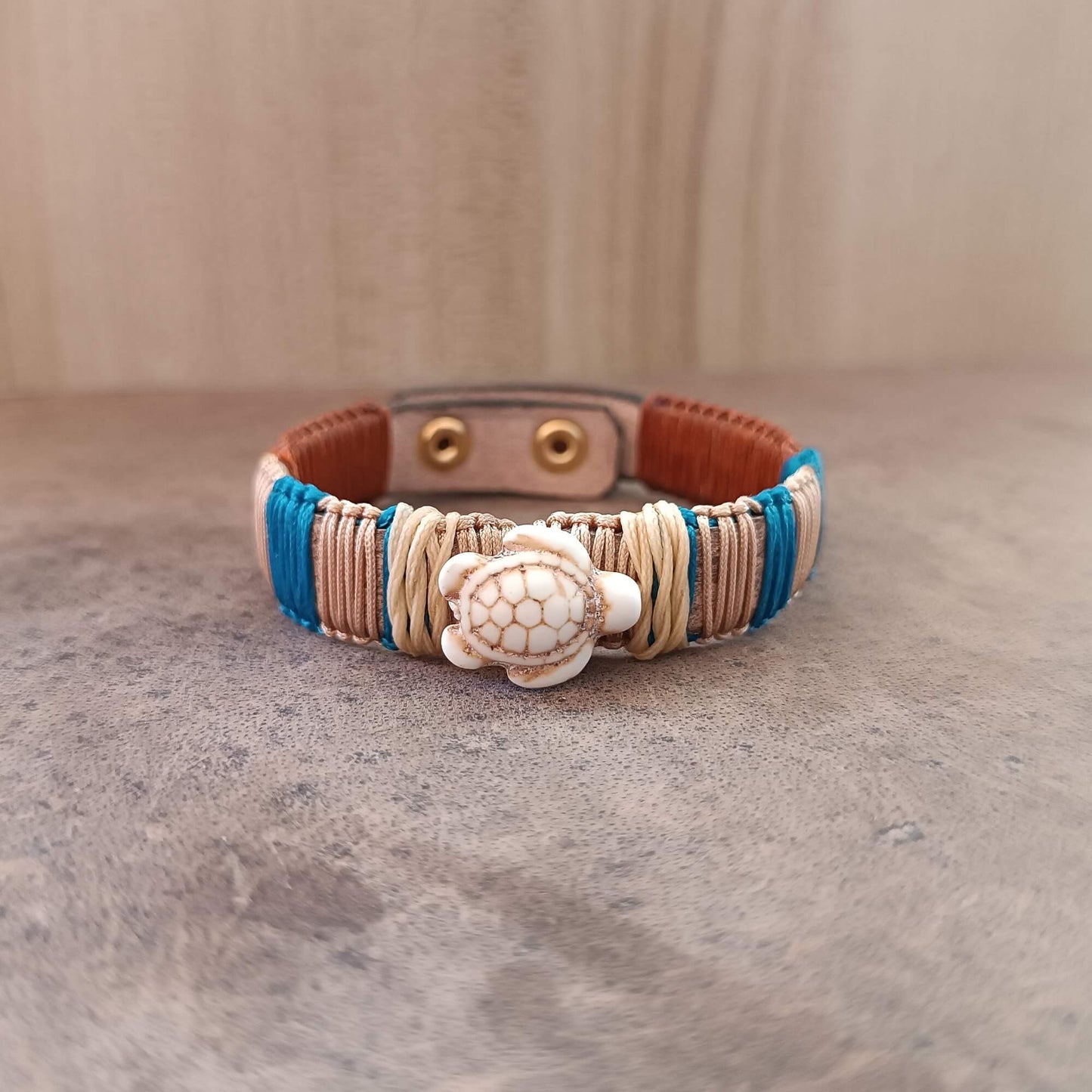 Bracelet with turtle charm on a textured surface