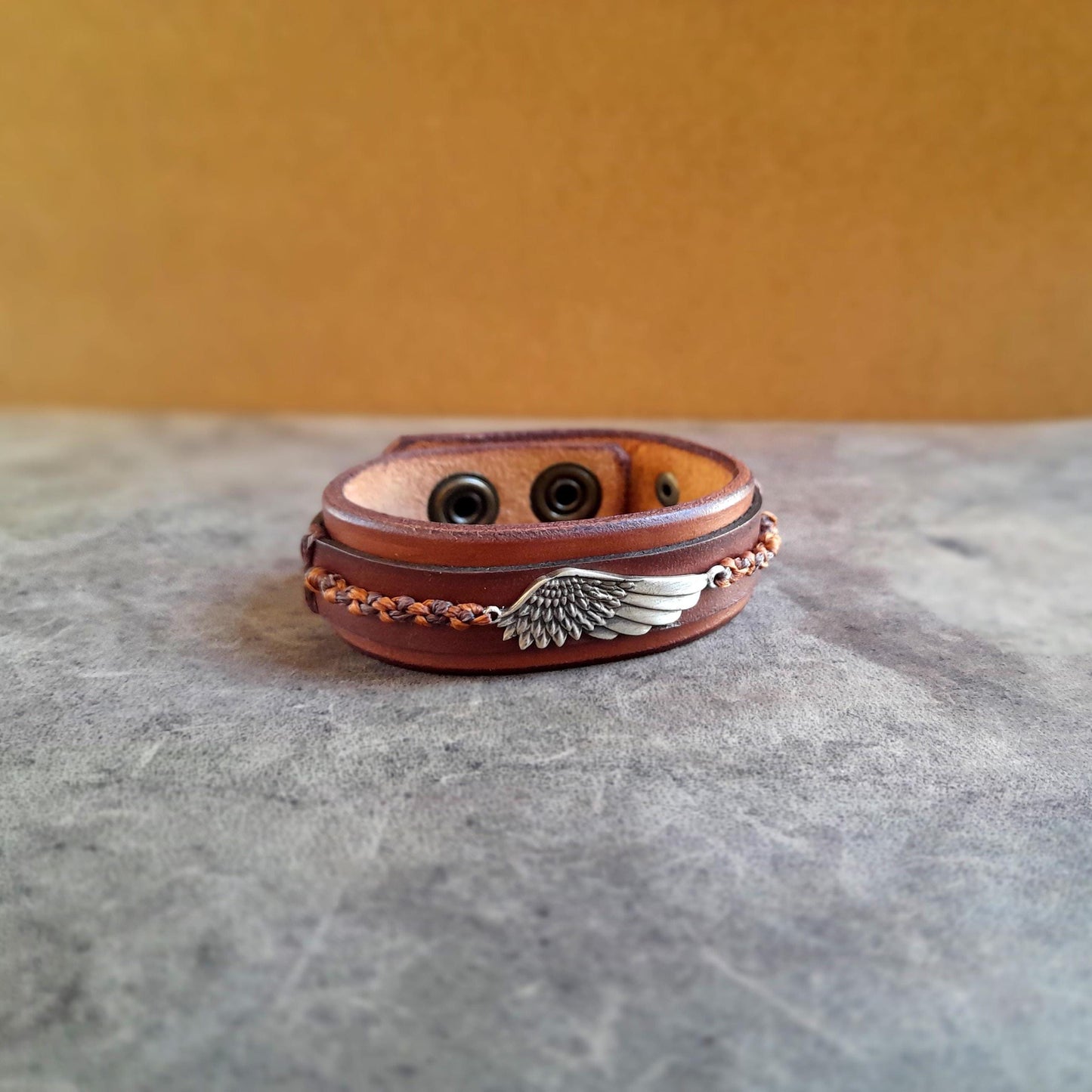 Symbolic wing leather bracelet featuring a hand-braided macrame wing on oiled Vachetta leather.