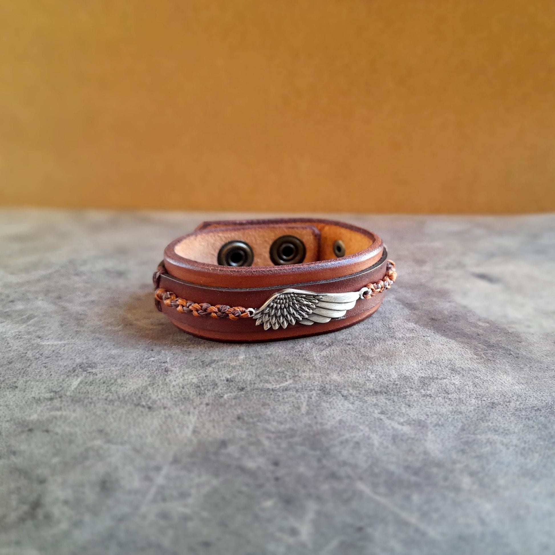 Symbolic wing leather bracelet featuring a hand-braided macrame wing on oiled Vachetta leather.