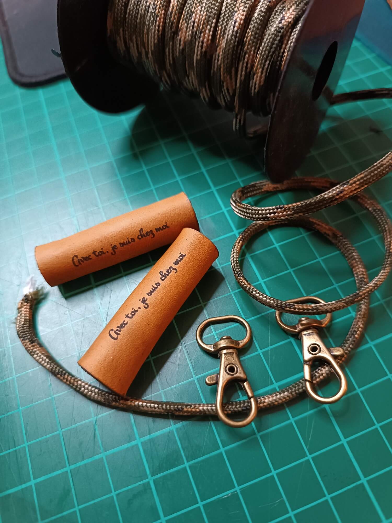 Brown leather keychain with rope and metal clasp on a green cutting mat